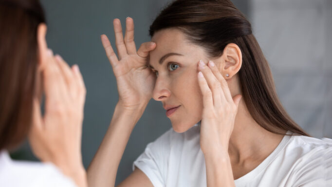 woman checking skin for blemishes